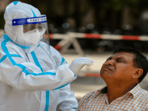 A healthcare worker administering a COVID-19 test to a patient in a medical setting, representing rising coronavirus cases in India